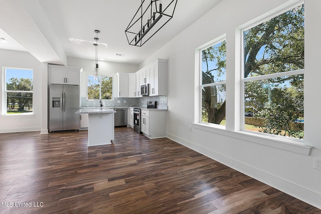 kitchen with dark hardwood / wood-style floors, stainless steel appliances, pendant lighting, and a kitchen island