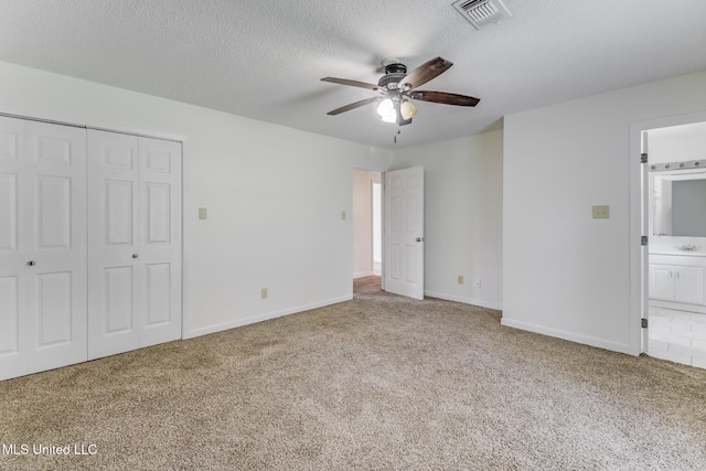 115 Shady Dr, Long Beach, MS 39560 - unfurnished bedroom with carpet floors, a closet, ensuite bath, a textured ceiling, and a ceiling fan