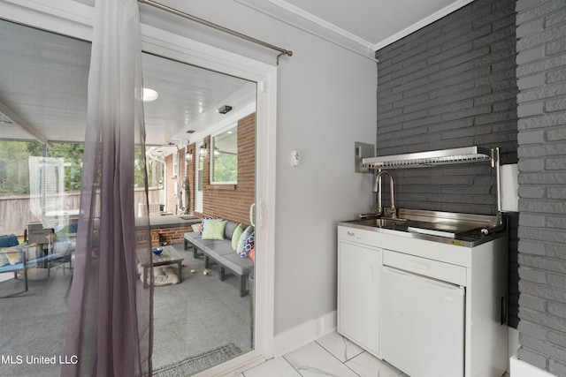 bathroom featuring brick wall, sink, and ornamental molding