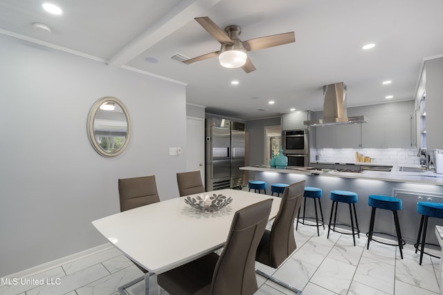 dining area with sink, crown molding, and ceiling fan