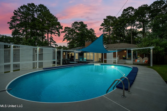 pool at dusk with a patio area