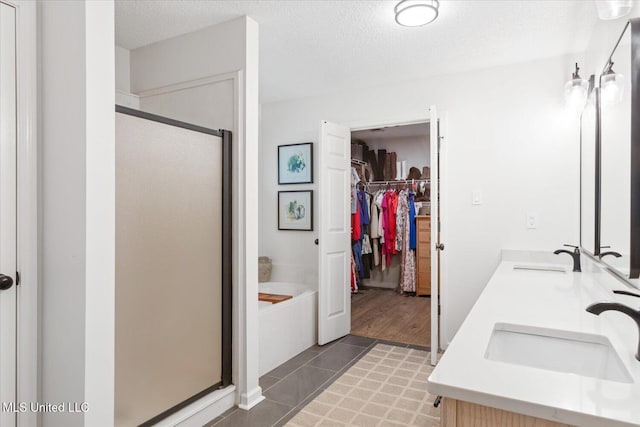 4275 Bienville Rd, Nesbit, MS 38651 - full bathroom with a stall shower, a walk in closet, double vanity, a bath, and a textured ceiling