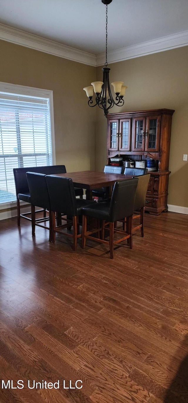 dining area featuring dark wood-style floors, crown molding, baseboards, and an inviting chandelier