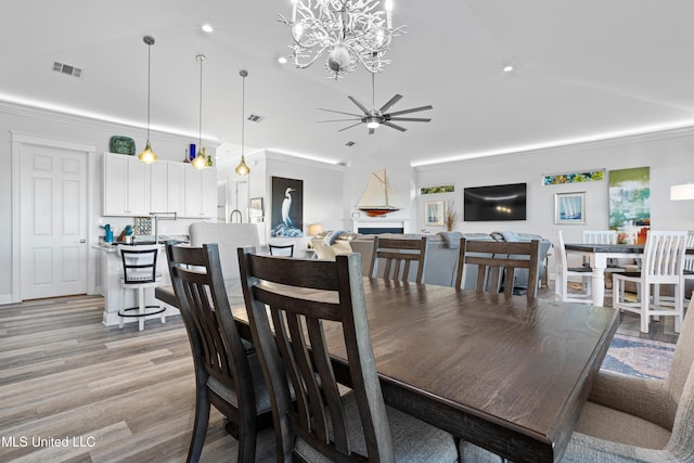 14 Sherman Ave, Pass Christian, MS 39571 - dining room featuring ceiling fan with notable chandelier, light wood-type flooring, visible vents, vaulted ceiling, and ornamental molding