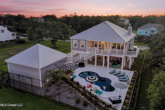 14 Sherman Ave, Pass Christian, MS 39571 - back of property at dusk featuring metal roof, a patio area, a fenced in pool, and stairway