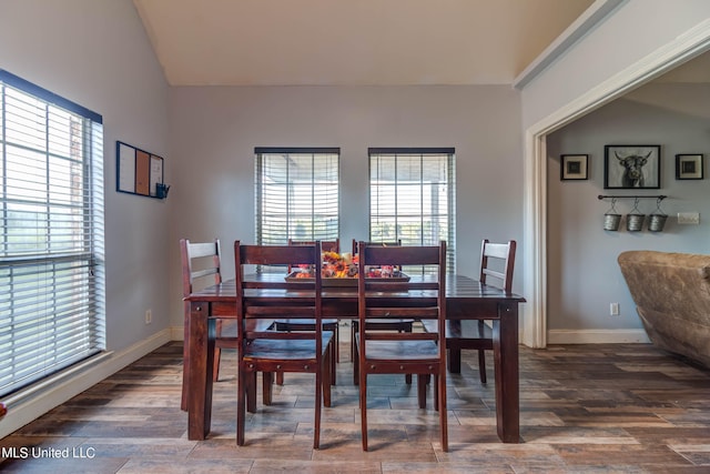 dining room with dark wood-type flooring, vaulted ceiling, and a wealth of natural light