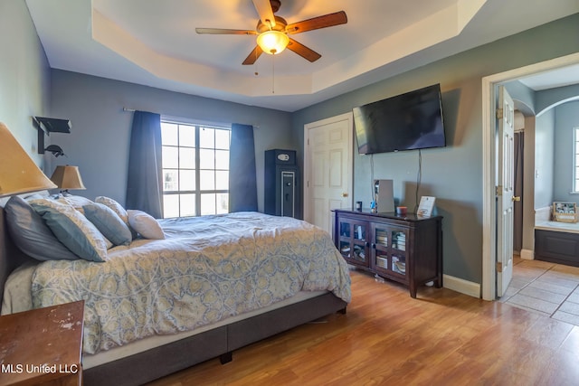 bedroom featuring light hardwood / wood-style floors, a tray ceiling, and ceiling fan