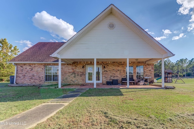 rear view of property with a yard, a patio, and a playground