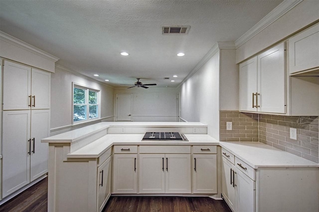 kitchen featuring dark wood-type flooring, crown molding, kitchen peninsula, and stainless steel gas cooktop