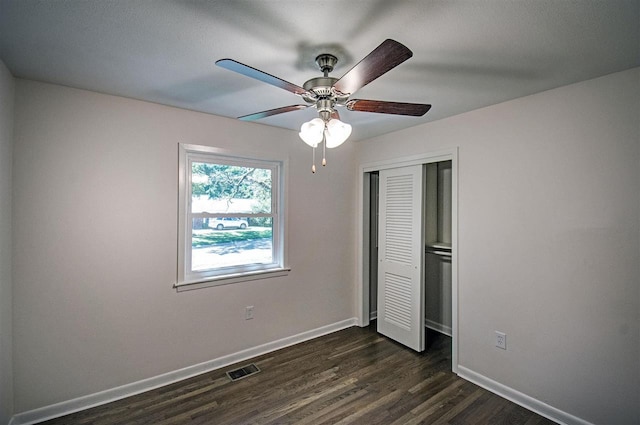 unfurnished bedroom featuring a closet, dark wood-type flooring, and ceiling fan