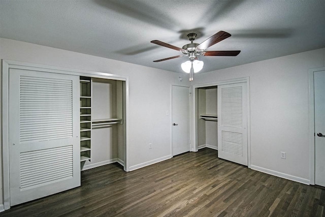 unfurnished bedroom featuring dark hardwood / wood-style flooring, two closets, a textured ceiling, and ceiling fan