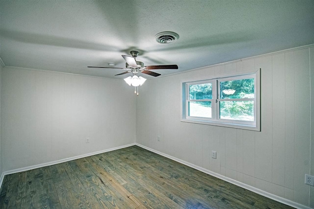 unfurnished room with wood walls, ornamental molding, dark wood-type flooring, and ceiling fan