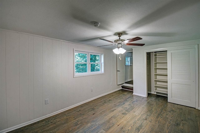 unfurnished bedroom featuring dark wood-type flooring, ceiling fan, a closet, and a textured ceiling