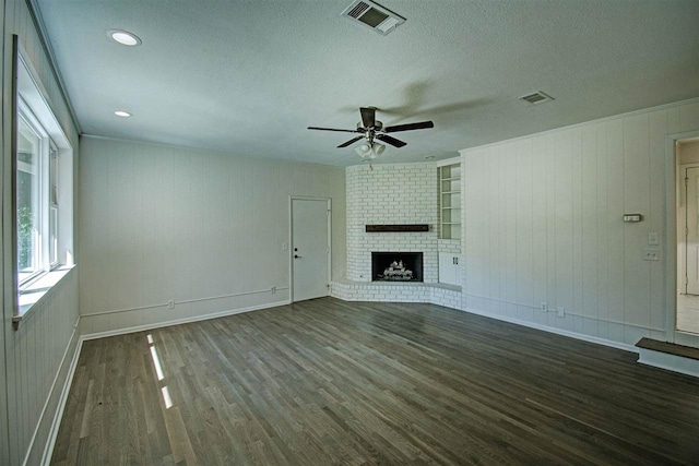 unfurnished living room with wood walls, a fireplace, a textured ceiling, dark hardwood / wood-style flooring, and ceiling fan