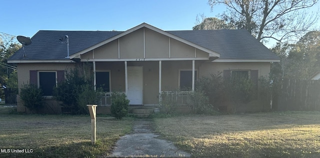 view of front facade with a porch, a front yard, and roof with shingles