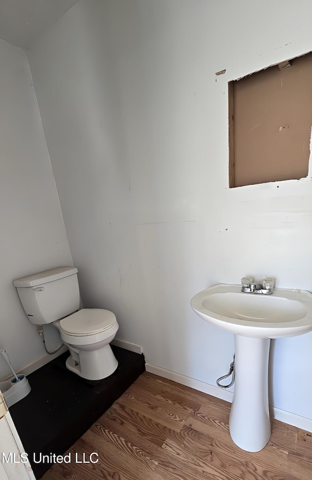 bathroom featuring toilet, baseboards, and wood finished floors