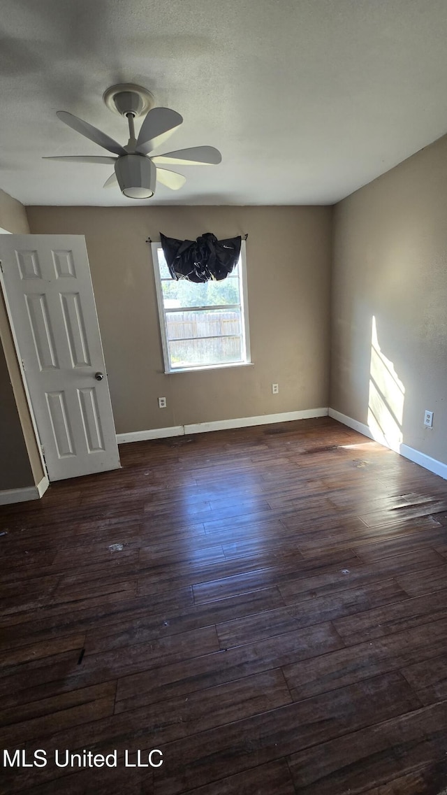 spare room with dark wood-style floors, baseboards, and a ceiling fan