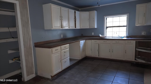 kitchen with tile patterned floors, white cabinetry, crown molding, and sink