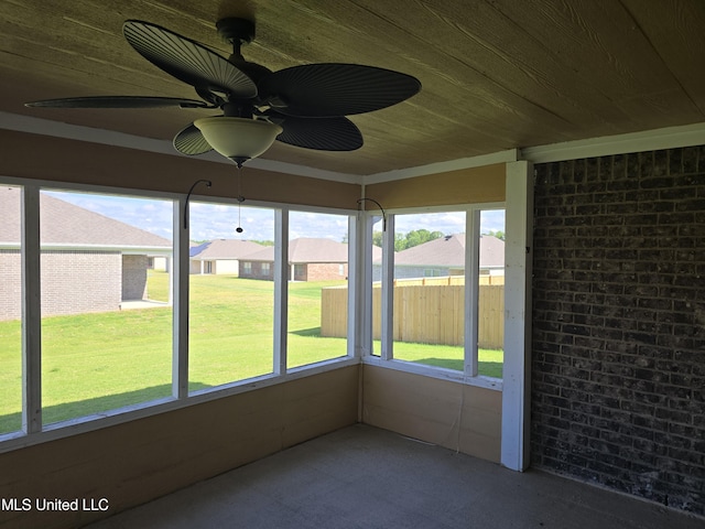 unfurnished sunroom featuring a residential view, ceiling fan, and a wealth of natural light