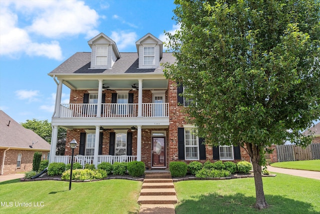 view of front of house with covered porch, a front yard, a balcony, and ceiling fan