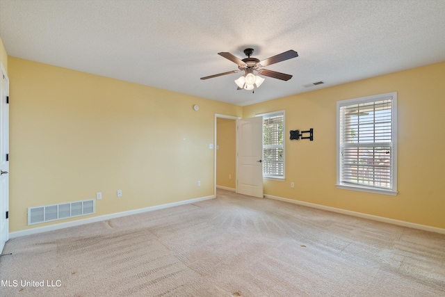 unfurnished room with a textured ceiling, light colored carpet, and ceiling fan