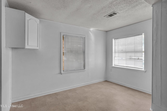 unfurnished room featuring baseboards, visible vents, a textured ceiling, and tile patterned floors