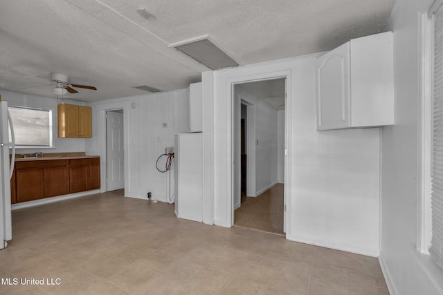 kitchen with a textured ceiling, ceiling fan, visible vents, light countertops, and freestanding refrigerator