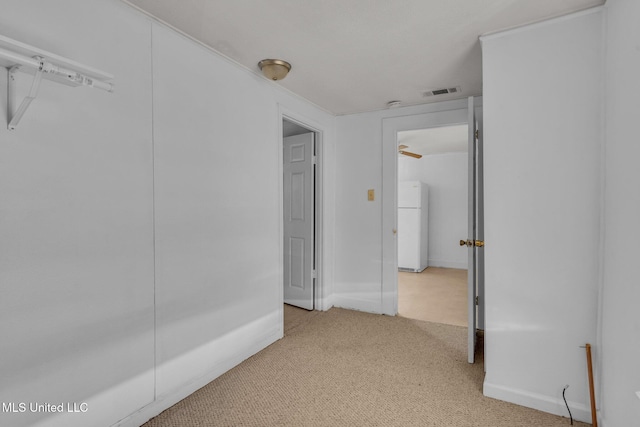 hall featuring baseboards, visible vents, and light colored carpet