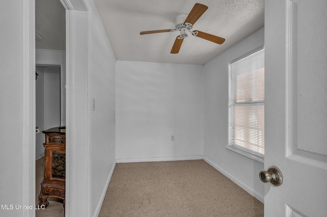 carpeted empty room featuring ceiling fan, a textured ceiling, and baseboards