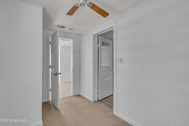 hall with light colored carpet, visible vents, and baseboards