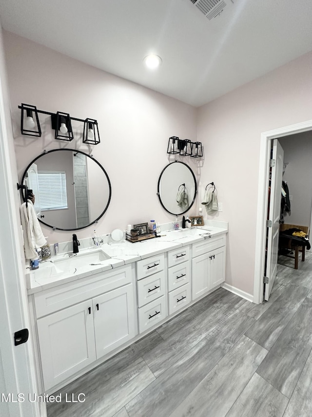 full bathroom with recessed lighting, visible vents, double vanity, and wood finished floors