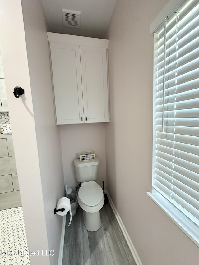 bathroom featuring visible vents, baseboards, toilet, and wood finished floors