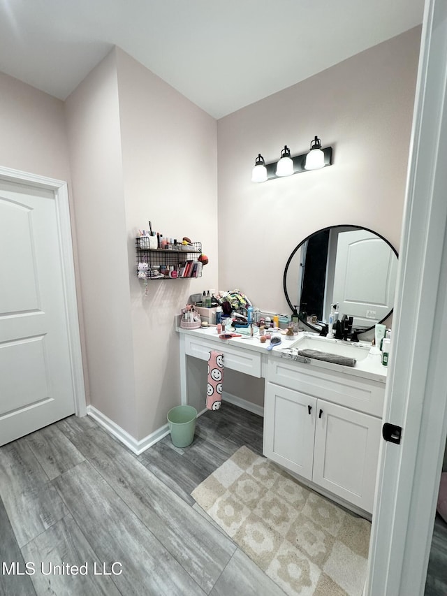 bathroom featuring baseboards, vanity, and wood finished floors