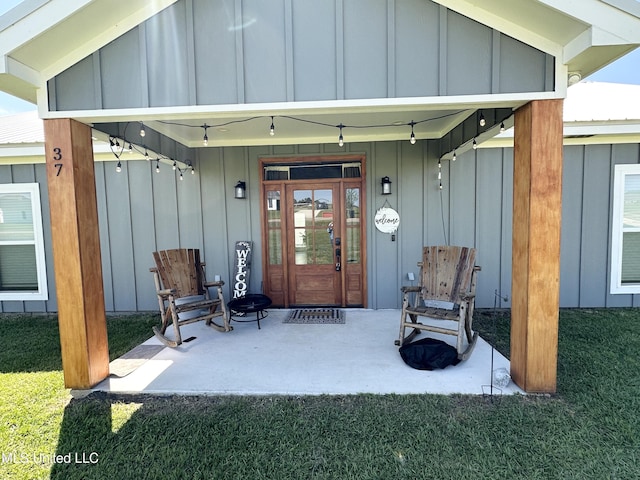 doorway to property featuring board and batten siding and a lawn