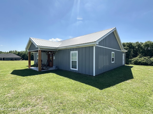 rear view of property with a yard, metal roof, and board and batten siding