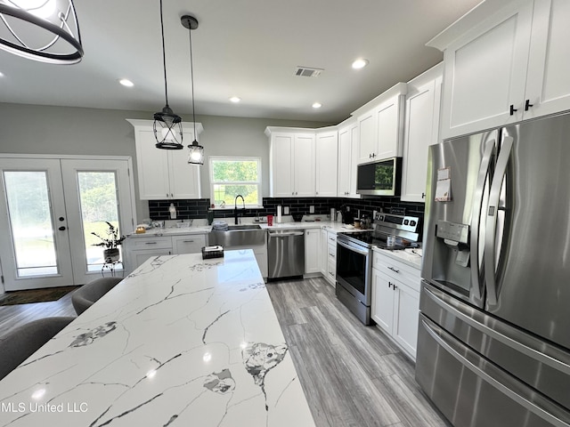 kitchen with visible vents, decorative backsplash, decorative light fixtures, and stainless steel appliances