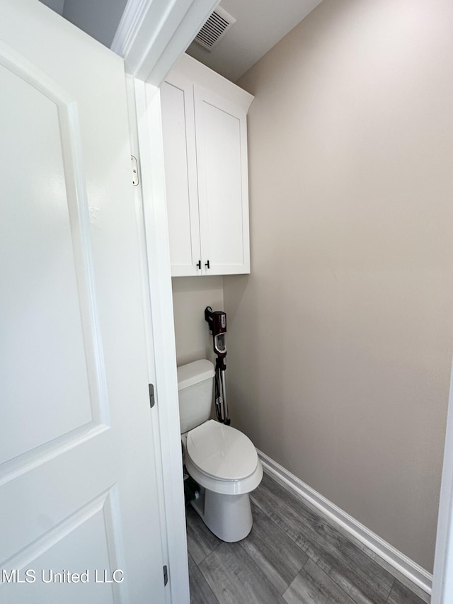 bathroom featuring toilet, wood finished floors, baseboards, and visible vents