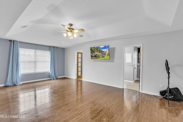 interior space featuring hardwood / wood-style floors, a textured ceiling, a raised ceiling, and ceiling fan