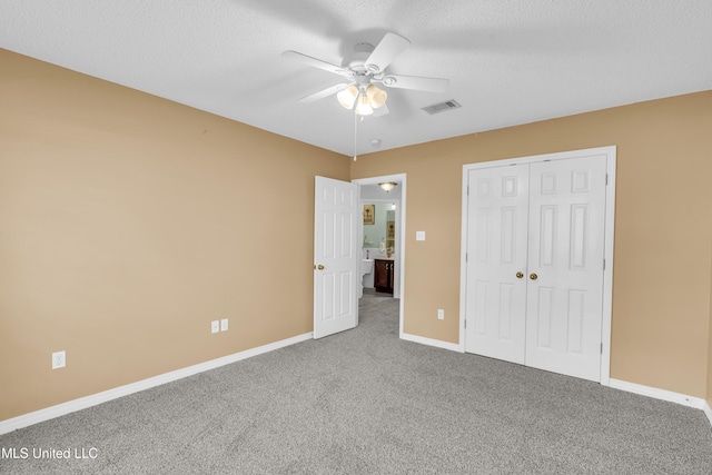 unfurnished bedroom featuring carpet, ceiling fan, a textured ceiling, and a closet