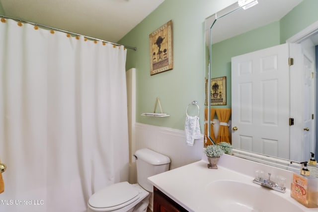 full bath with a shower with curtain, vanity, toilet, and wainscoting