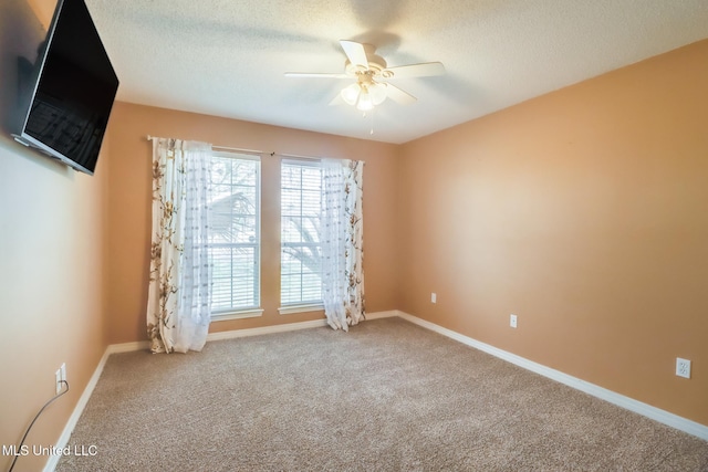 empty room with carpet flooring, a textured ceiling, baseboards, and a ceiling fan