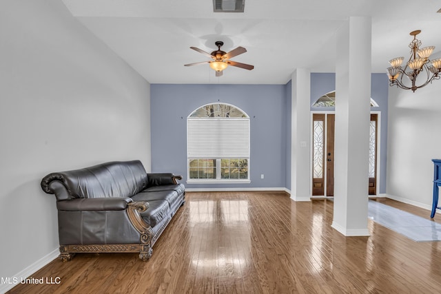 living area with visible vents, wood-type flooring, baseboards, and ceiling fan with notable chandelier