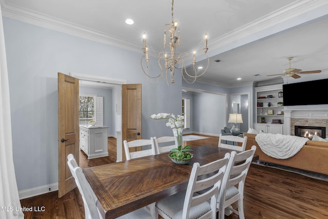 dining area featuring built in shelves, ornamental molding, dark hardwood / wood-style flooring, and a stone fireplace