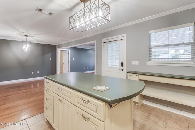 31 55th St, Gulfport, MS 39507 - kitchen featuring cream cabinetry, dark countertops, ornamental molding, light tile patterned floors, and a center island
