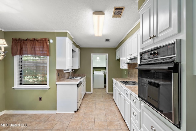 kitchen with washer / dryer, oven, sink, white cabinetry, and ornamental molding