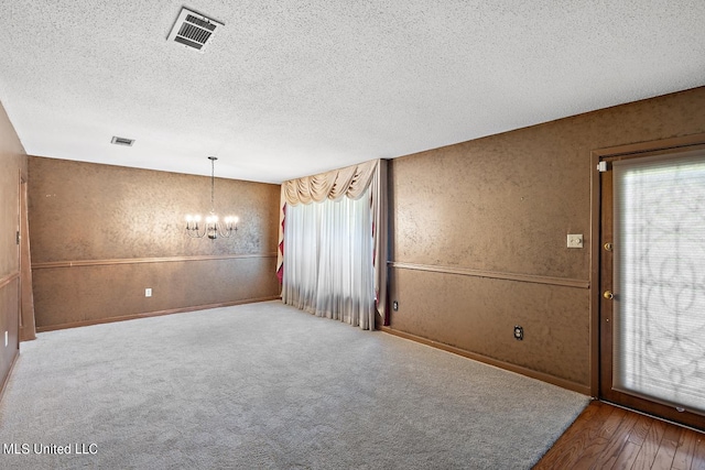 spare room with an inviting chandelier, hardwood / wood-style floors, and a textured ceiling