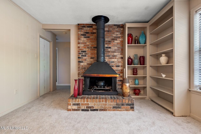 living room with a wood stove, a textured ceiling, light carpet, wooden walls, and ornamental molding