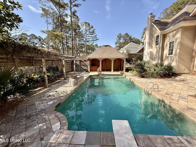 pool featuring a patio area, a fenced backyard, a diving board, and an outbuilding