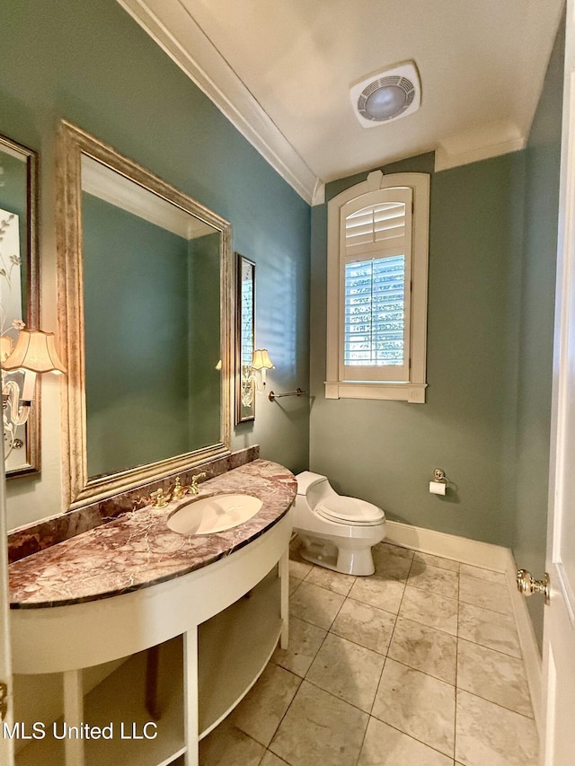 half bath featuring tile patterned flooring, toilet, vanity, baseboards, and crown molding