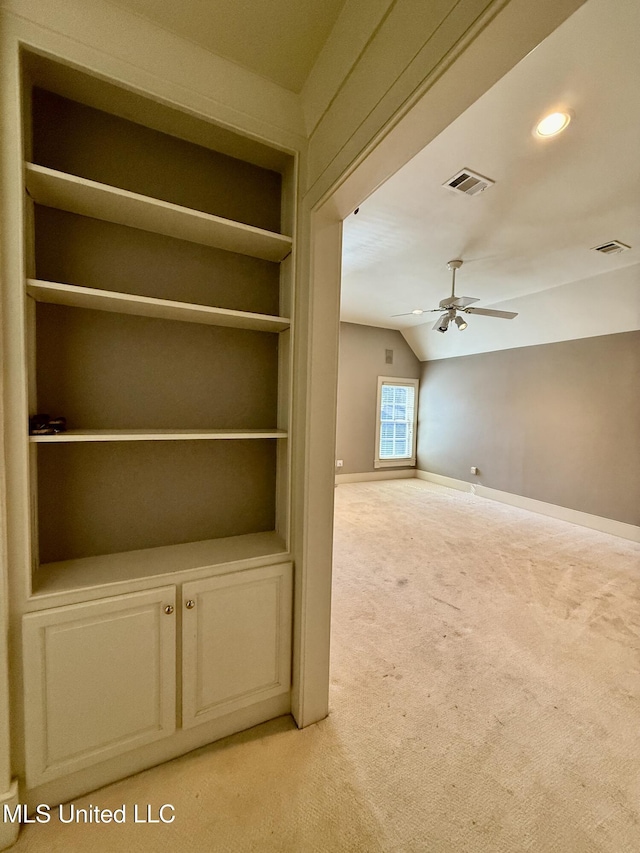 interior space with light carpet, visible vents, built in features, baseboards, and lofted ceiling